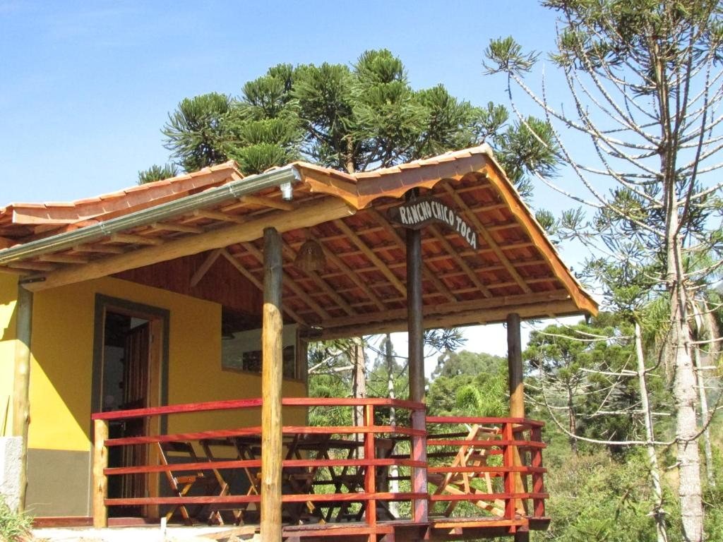 Varanda de madeira entre araucárias na pousada